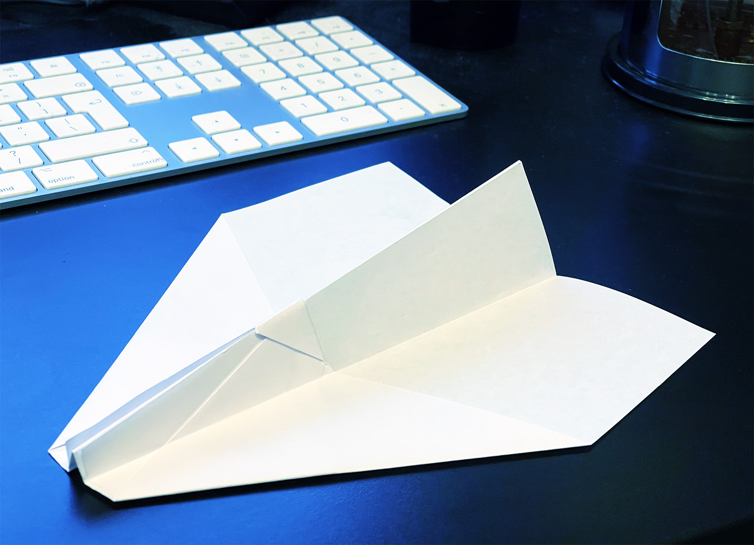 The paper plane, upside down on a desk